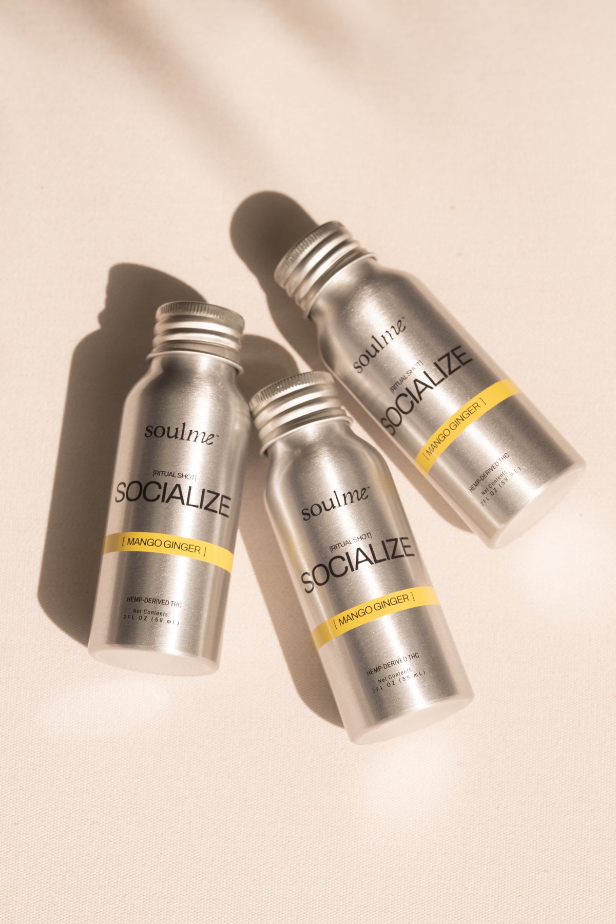 Three SoulMe Socialize Ritual Shot bottles in mango ginger on warm linen